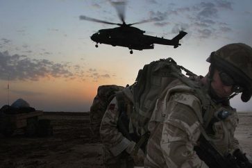 SHALAMCHEH, IRAQ - FEBRUARY 06:  A British soldier turns away as RAF Merlinhelicopter lands at FOB Minden at forward operating base close to the Shalamcheh land border crossing at the Iraq-Iran border on February 6, 2009 in Iraq. British troops led by the Queen's Royal Hussars and based FOB Minden, have been recently assisting with border security and mentoring the Iraqi Directorate of Border Enforcement (DBE) and the Iraqi Police. The border crossing point, which was closed during the recent elections, has been reopened and is often used in large numbers by Iranian Shia Muslim pilgrims travelling to the holy sites in Karbala and Najaf in Iraq.  (Photo by Matt Cardy/Getty Images)