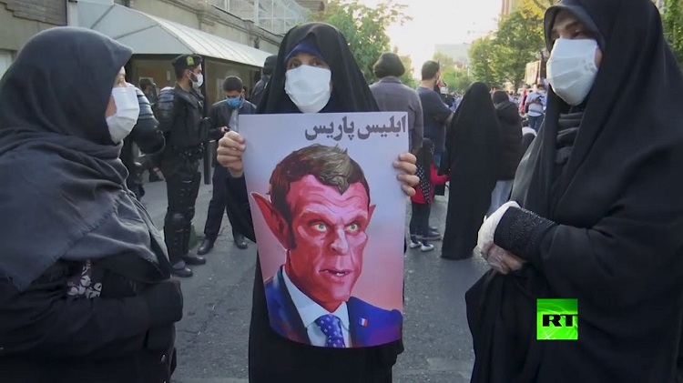 Un portrait caricaturiste, représentant Macron sur lequel est inscrit 'le Satan de Paris', brandi par une manifestante iranienne à Téhéran